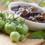 "Ingrédients frais pour préparer la confiture de tomates vertes sur un comptoir en bois rustique."